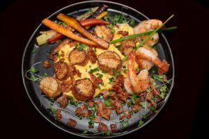 Scallops and shrimp plated with bacon and vegetables