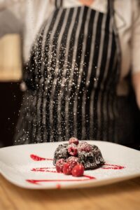 Chocolate Dessert with fresh raspberries being frosted with powdered sugar